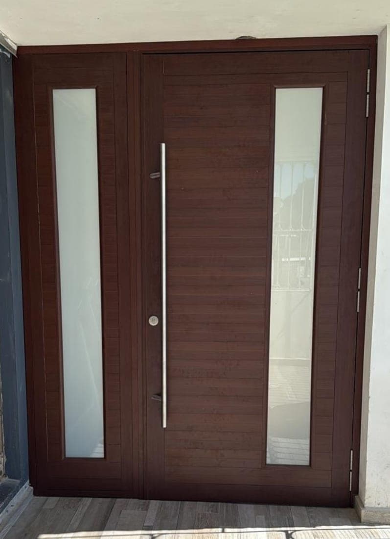 Puerta doble de entrada en acabado madera con cristales verticales