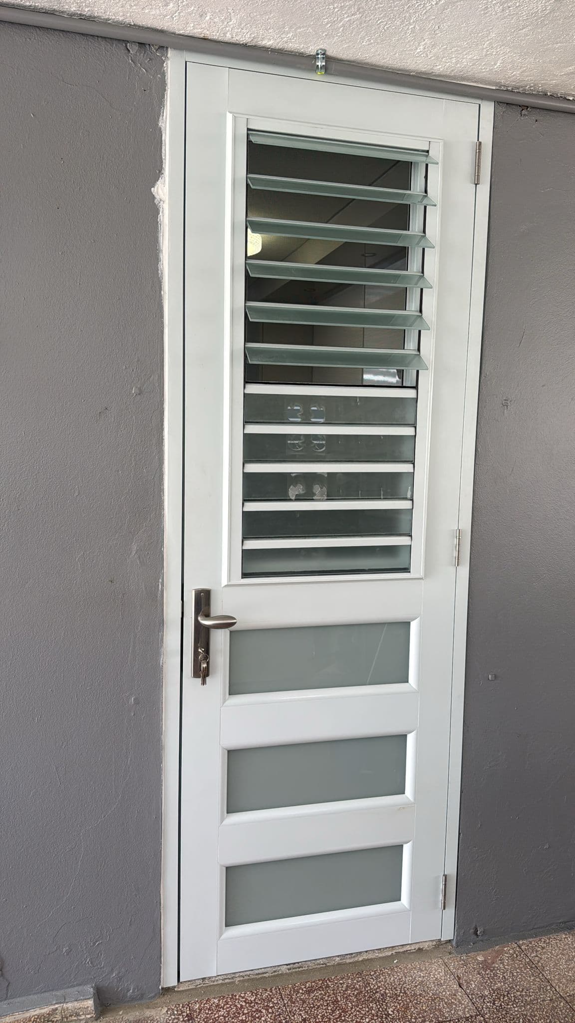 Puerta blanca junto a ventanas tipo celosía